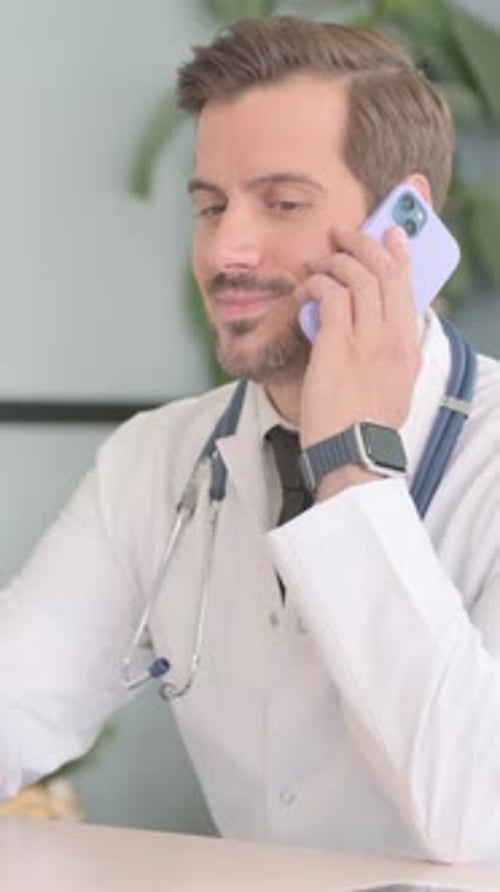 Male Doctor Talking on Phone in Clinic, vertical video