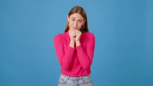 Hopeful Woman Gesturing in Front of Blue Background