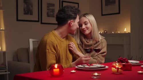 Glückliches junges Paar, das verliebt ist, umarmt, lacht, trinkt Wein, genießt es zu reden, zu haben