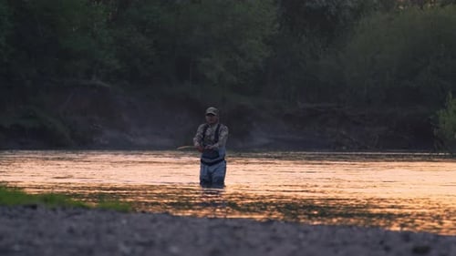 Fly fishing. Fisherman casts fly on the river at sunset. Caucasian amateur angler fishing on the riv