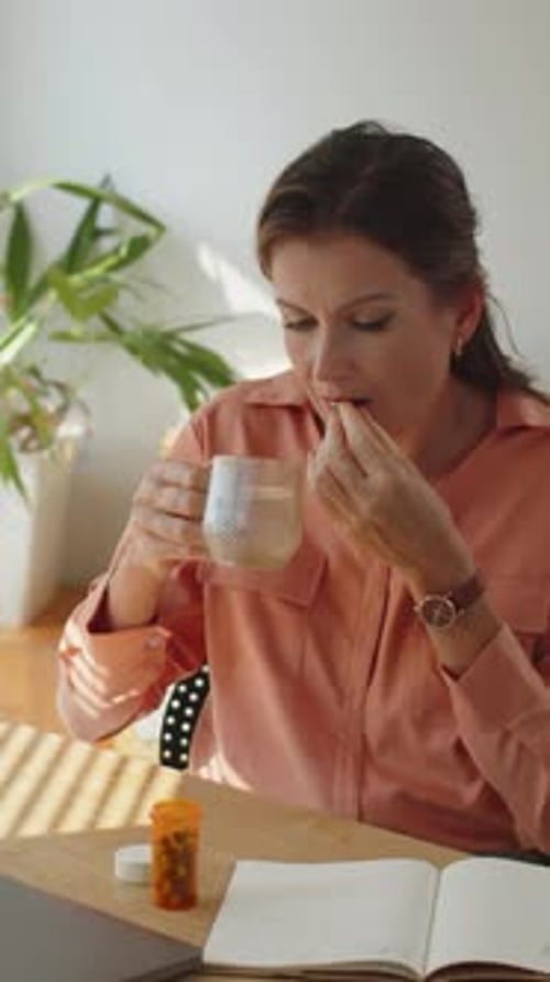 Woman Takes Pill With Glass of Water