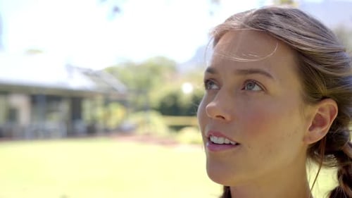 Smiling woman looking up, enjoying sunny day outdoors in garden, copy space