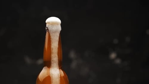 Foamy Beer Pouring Out of Bottle