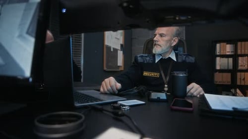Security Guard Monitoring Screens in a Dark Office