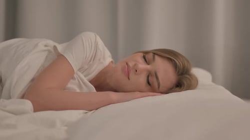 Side View of Young Woman Sleeping in Bed at Home