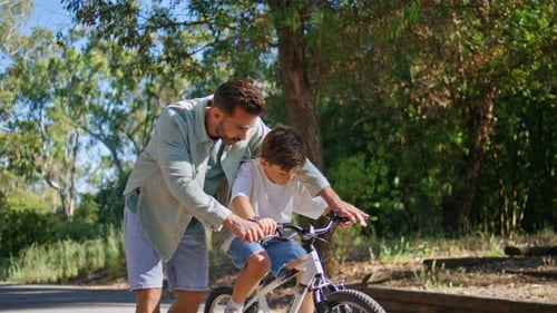 Father Helping Son Ride Bicycle in Sunbeams Park Small Child Learning Cycling