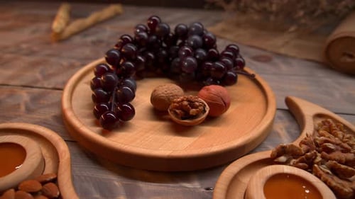 Grapes, Nuts and Honey on Wooden Dishes
