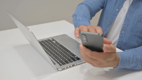 Close up of Man Using Laptop and Smartphone
