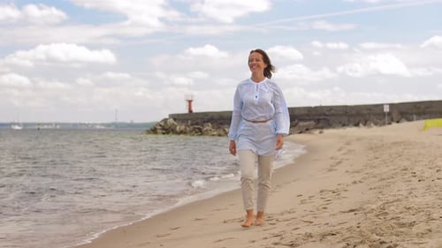 Happy woman walking along a summer beach enjoying leisure and the seaside
