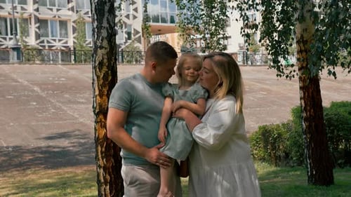 Portrait of a smiling young family mom dad and little daughter family on a walk in the park happy
