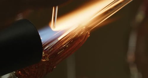 Flüssiges Glas wird von einem Glasbläserkünstler auf ein Kunstwerk geschmolzen