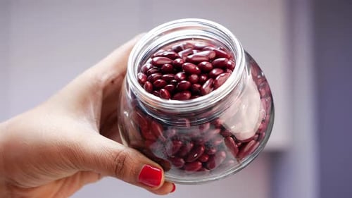 Hand Tilts Jar of Kidney Beans and Pours