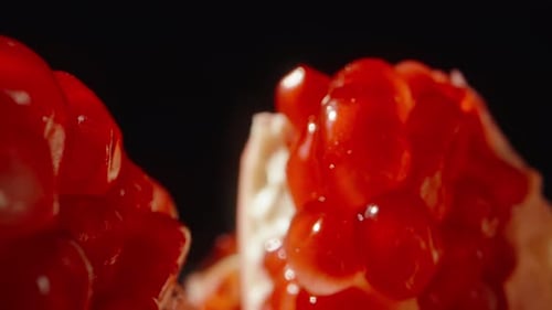 A chopped pomegranate with red grains, the camera rides through it. Dolly slider extreme close-up.