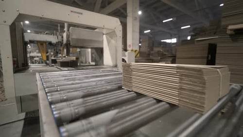 Machine Delivers Stacks of Cardboard Sheets to Packing Area