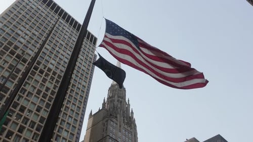 American Flag Waving in Wind with City Buildings