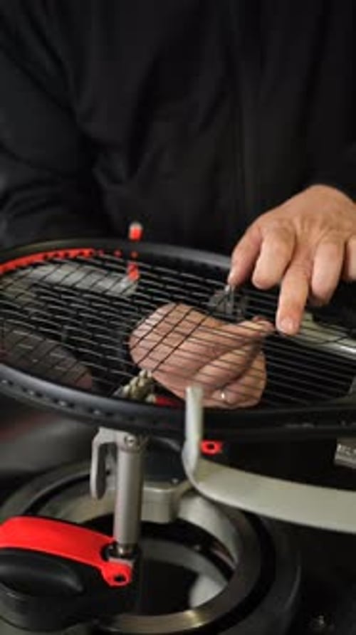 Un técnico experto ata cuidadosamente una raqueta de tenis con una máquina especializada