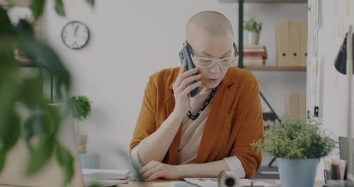 Cheerful Business Owner Speaking on Mobile Phone Laughing and Working with Laptop in Office