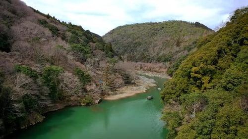 Wunderschöne Drohnenaufnahme eines Bootes auf einem Fluss in Kyoto, Japan