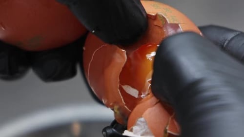 Close-up of egg yolk on fresh cheese for pie. Woman wearing gloves mixing ingredients
