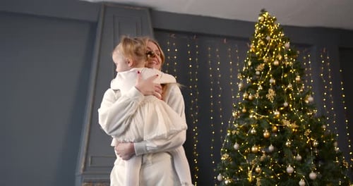 Young Woman Holding Little Daughter Near Christmas Tree