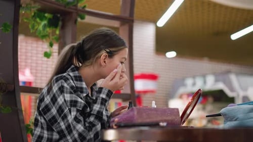 Teen Girl Applies Makeup at Table with Mirror