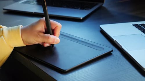 Graphic designer illustrator drawing on laptop with graphics tablet