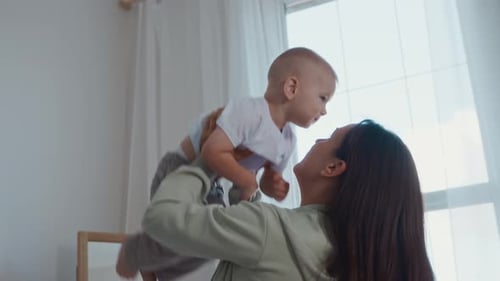 Mother happily holds infant child, laughing, loving moments
