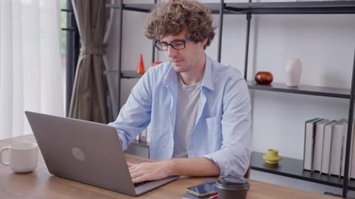Young Adult Works on Laptop in Home Office