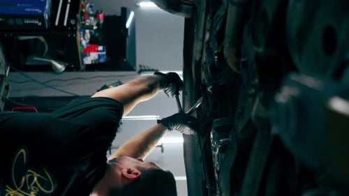 Vertical Video Close Up an Auto Mechanic at Service Station Checks a Car Being Lifted on a Lift