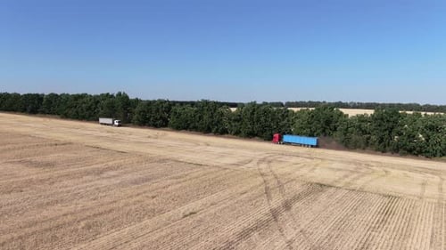 Trucks Driving on Rural Road Near Field