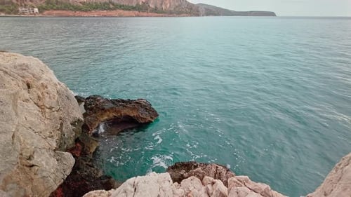 Hermosas olas de mar azul claro salpican contra la rocosa costa costera