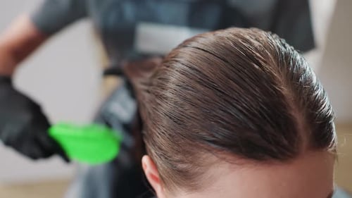 Salon Professional Gently Smoothing Brown Hair at Hairline Detailed Shot of Stylist Using Green