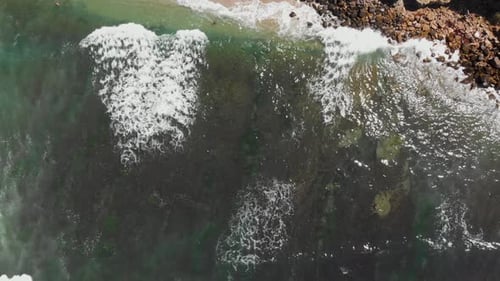 Top down aerial shot over the whitecaps as they crash on the San Diego coastline.