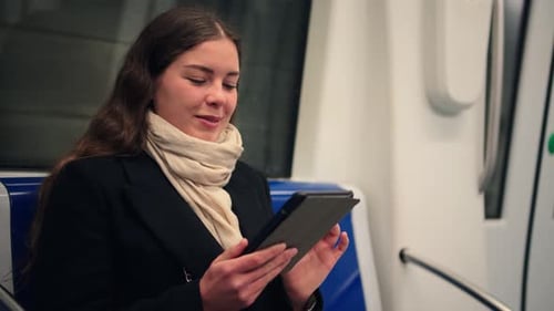 Woman Comfortably Reading on an Ereader While Sitting on a Subway Train During Her Daily Commute
