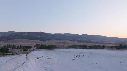 Vista aérea de travertinos ao nascer do sol com balões de ar quente, Turquia.
