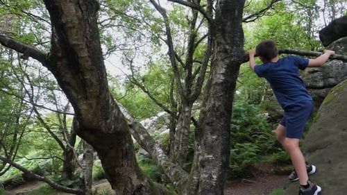 Junge klettert und springt auf die Felsen von Brimham Rocks, einst bekannt als Brimham Crags in North Y