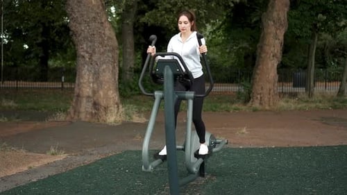 Woman Engaging in Outdoor Fitness Workout on Exercise Equipment in Park During Daytime