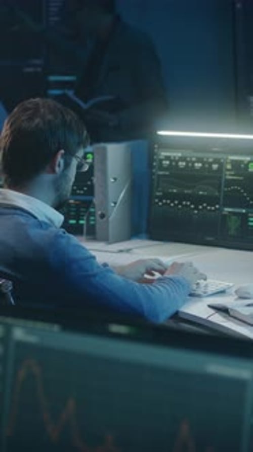 Young Adult Typing at Computer in Dark Office