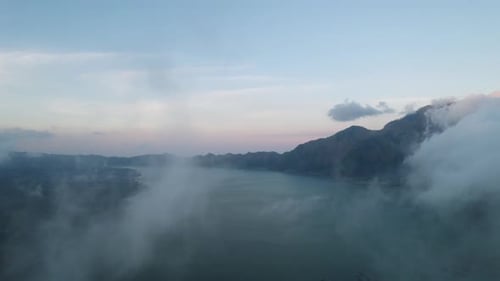 Cirrus clouds moving over a lake near Mount Batur during sunrise. Drone tilt shot
