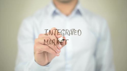 Man Writing Integrated Marketing on Transparent Surface