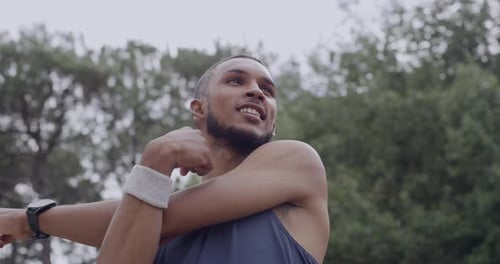 Young male athlete stretching arms to prepare his body for a workout in a park
