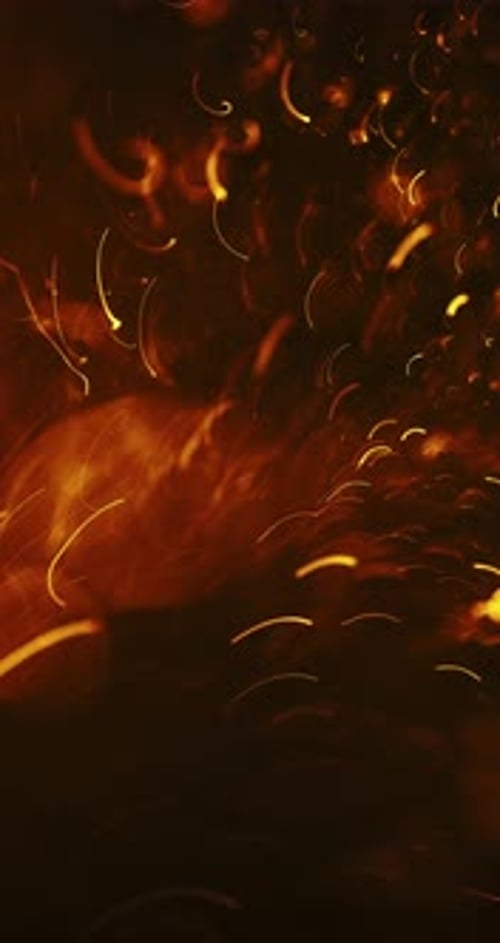 Particules jaune vif et orange tourbillonnant dans l'obscurité