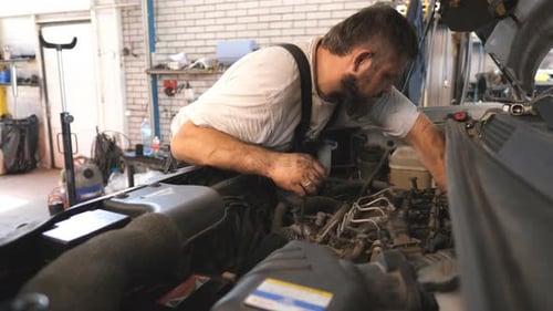 Mechaniker repariert den Motor eines Autos in einer Werkstatt oder einem Service Professioneller Automechaniker arbeitet unter der Motorhaube