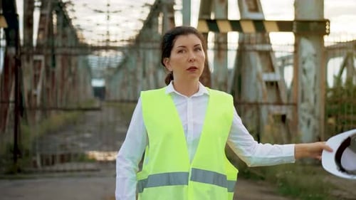 Tired Supervisor Woman Taking of Work Helmet at Bridge Construction and Wipes Forehead Brunette