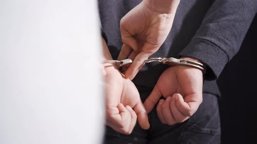 The criminal male was handcuffed by the police.