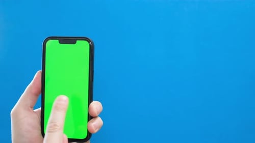 Green Smartphone Screen on a Blue Background Closeup of a Man's Hand Using a Smartphone Chromakey