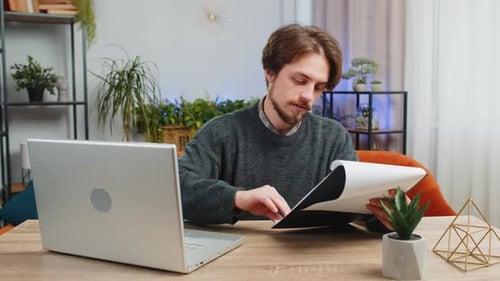Man working from home office with laptop and papers