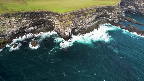 Aerial view of crispy waves breaking on the cliffs along the coastline in Iceland.
