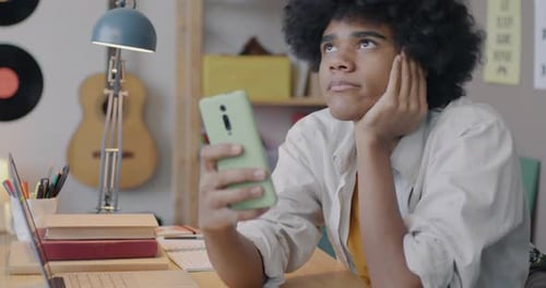 Young Adult Using Cell Phone at Desk