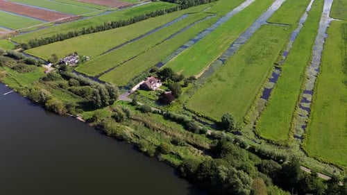 Aerial view of a rural landscape with central road water body irrigated fields and scattered houses.